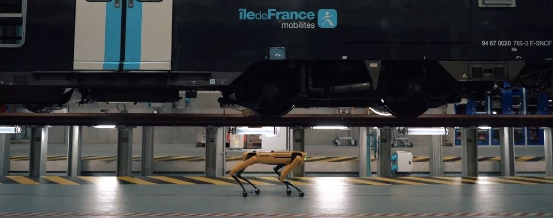 Le robot Spot marche devant une rame de train 2 niveaux